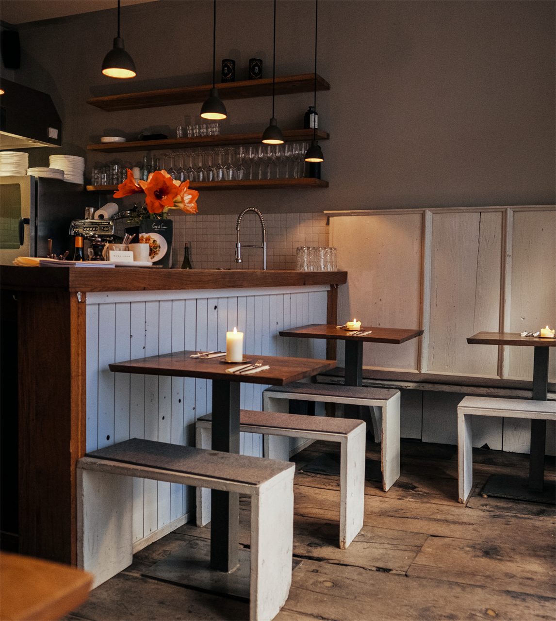 Warmes Interieur des Restaurants Coup de Cœur mit Holztischen und Pendelleuchten